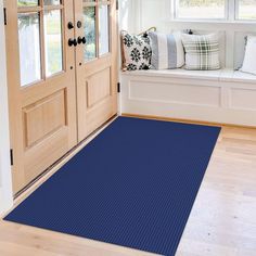 a blue rug in front of a wooden door with pillows on the window sill