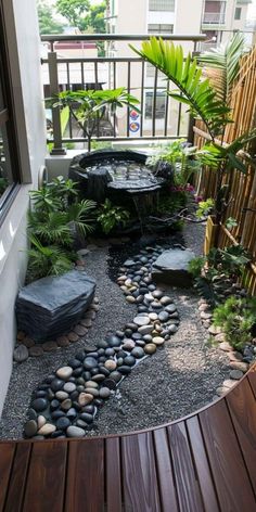 a small garden with rocks and plants on the ground next to a wooden decking area