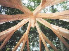 looking up at the top of a wooden structure with lots of trees in the background