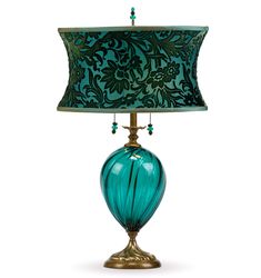 a green lamp with a blue shade on it's side and a gold base