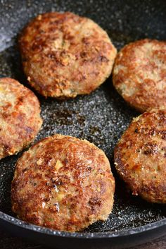 four hamburger patties cooking in a frying pan