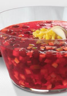 a glass bowl filled with food and garnish on top of a white table