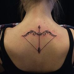 the back of a woman's neck with an arrow tattoo