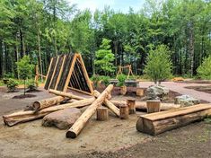 a group of logs sitting on top of a dirt field next to some rocks and trees