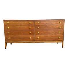 a large wooden dresser with brass knobs on the top and bottom drawers, against a white background