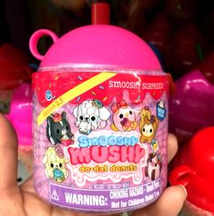 a hand holding up a pink cup with cartoon characters on it