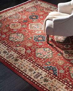 a red rug with an ornate design on the floor and chair in front of it