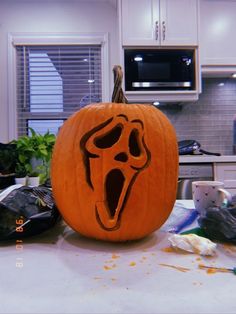 a carved pumpkin with a ghost face on it's head and mouth is sitting on a kitchen counter