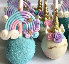 cake pops with unicorn decorations on them and candles in the top one is pink, purple, blue