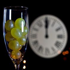 grapes in a wine glass next to a clock