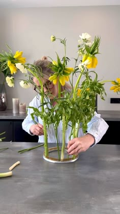 a woman is arranging flowers in a vase