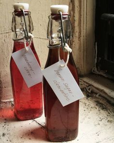 two bottles with labels on them sitting next to each other in front of a window