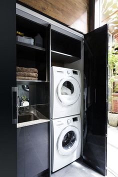 a washer and dryer in a room with open shelves on the wall next to each other