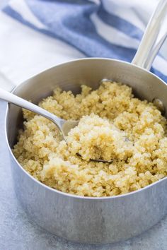 a bowl filled with rice on top of a blue and white towel next to a spoon