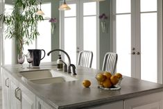 a kitchen counter with two sinks and some fruit on the table in front of it