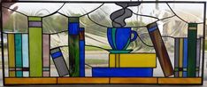 a stained glass window with books and a cup