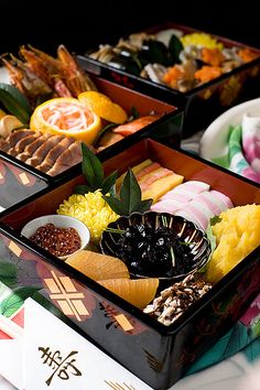 three trays filled with different types of food on top of a white table cloth