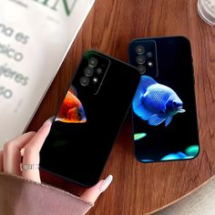 two cell phones with different colored fish on them sitting on a table next to each other