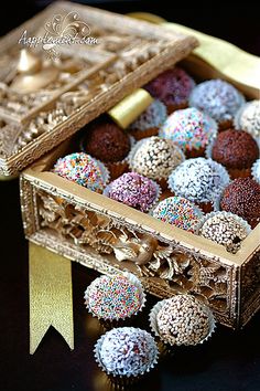 a box filled with assorted chocolates next to a golden ribbon on a table