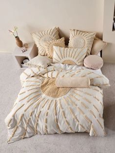 a bed with white and gold comforters in a bedroom next to a nightstand on the floor