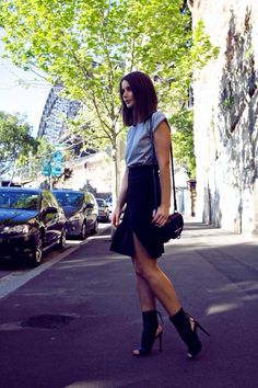 a woman is standing on the street with her hand in her pocket and looking up