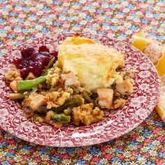 a red and white plate topped with food on top of a table next to lemon wedges