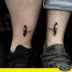 two people with matching tattoos on their legs, one has an alien face and the other has a cat's head