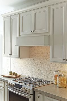 a stove top oven sitting inside of a kitchen next to white cabinets and counter tops