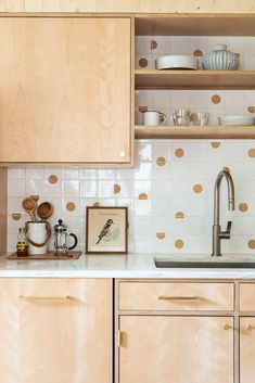 a kitchen with wooden cabinets and white tile backsplash, gold polka dots on the wall