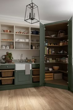 an open kitchen with green cabinets and white cupboards on the wall, next to a wooden floor