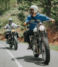 two men riding motorcycles down the road