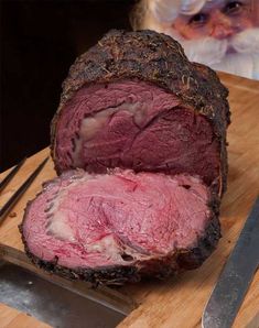 a large piece of meat sitting on top of a cutting board next to a knife