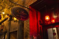 a restaurant sign hanging from the side of a brick building with red lights on it