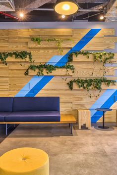 an office lobby with blue and yellow benches, plants on the wall, and wooden slatted walls