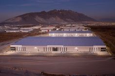 an aerial view of a warehouse building with mountains in the background at night, lit up by street lights