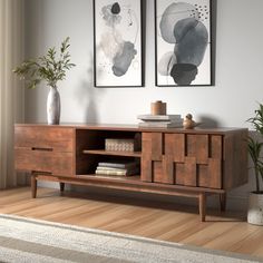 a living room with two paintings on the wall and a wooden cabinet in front of it