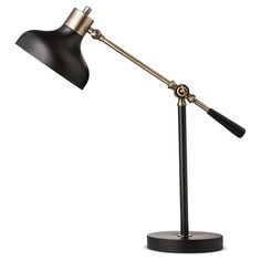 a black and gold desk lamp on a white background with clippings to the side