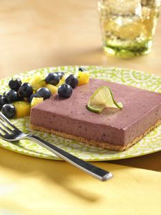 a piece of cake on a plate with blueberries and limes next to it