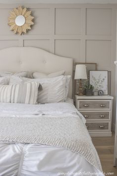 a white bed topped with lots of pillows next to a night stand and nightstands