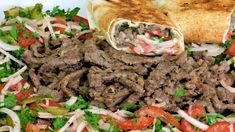 a plate filled with meat and veggies next to a pita bread roll