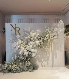 an arrangement of white flowers in front of a wall with the letter n on it