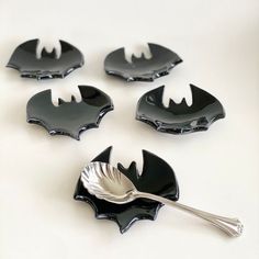 four black and white batman themed dishes with silver spoons