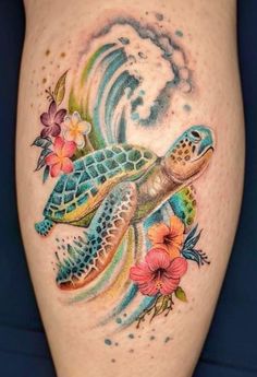 a tattoo on the leg of a woman with a sea turtle and flowers around it