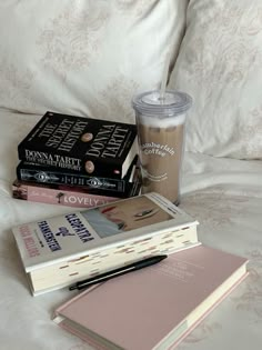 three books and a cup on a bed