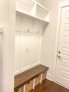 a wooden bench sitting in the middle of a room next to a white closet door