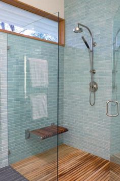 a bathroom with a glass shower and wooden flooring next to a walk in shower