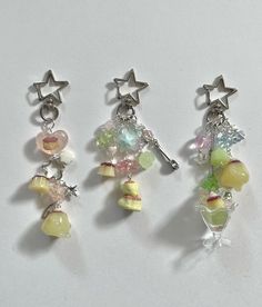 three charms are hanging from the side of a white surface, each with different colors and shapes