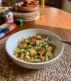 a white bowl filled with food sitting on top of a table next to a fork