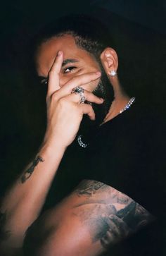 a man with tattoos holding his hand to his face