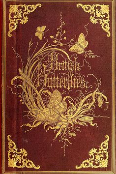 an old red book with gold trimmings and butterflies on the cover, sitting on a table